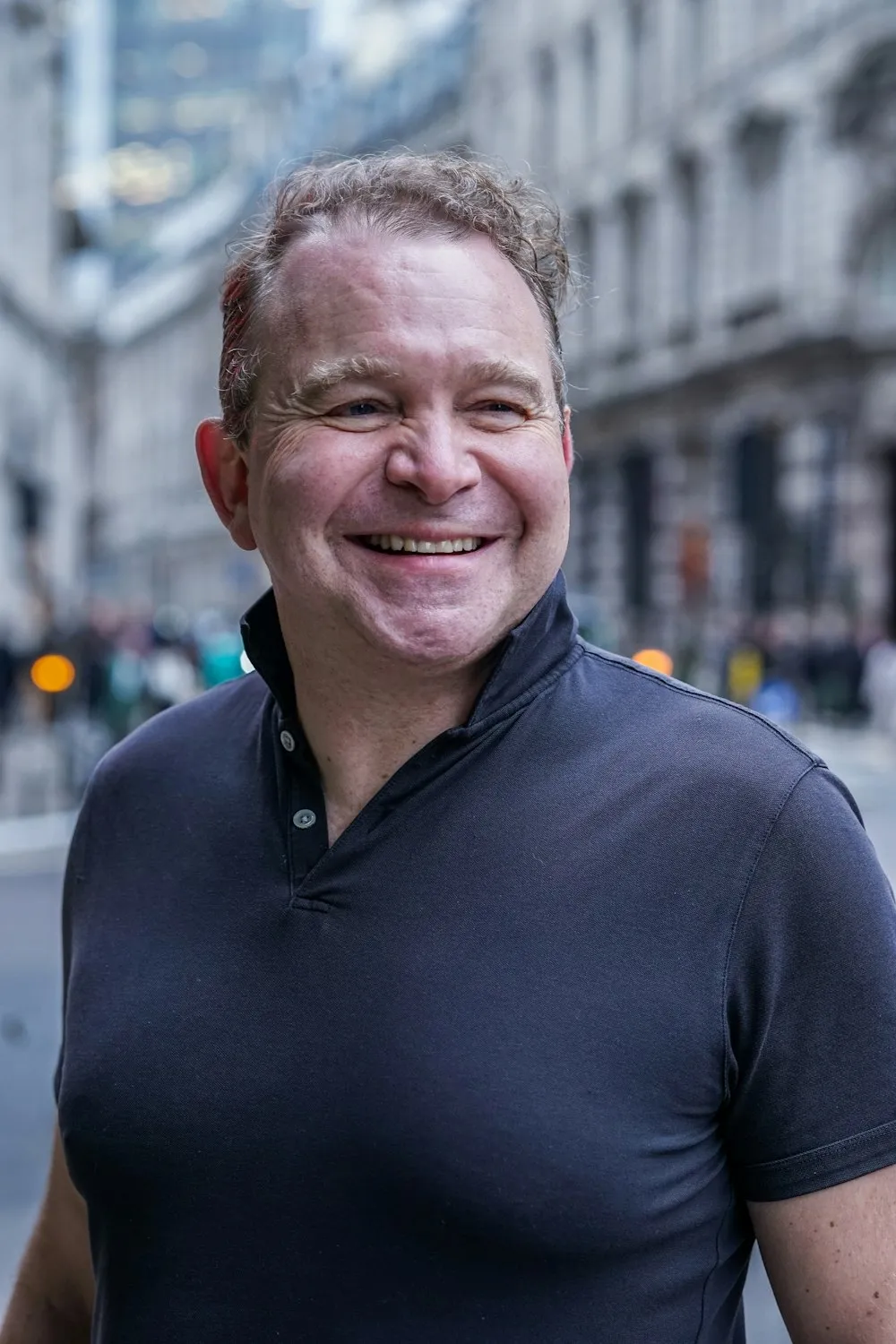 A man smiling on a city street.