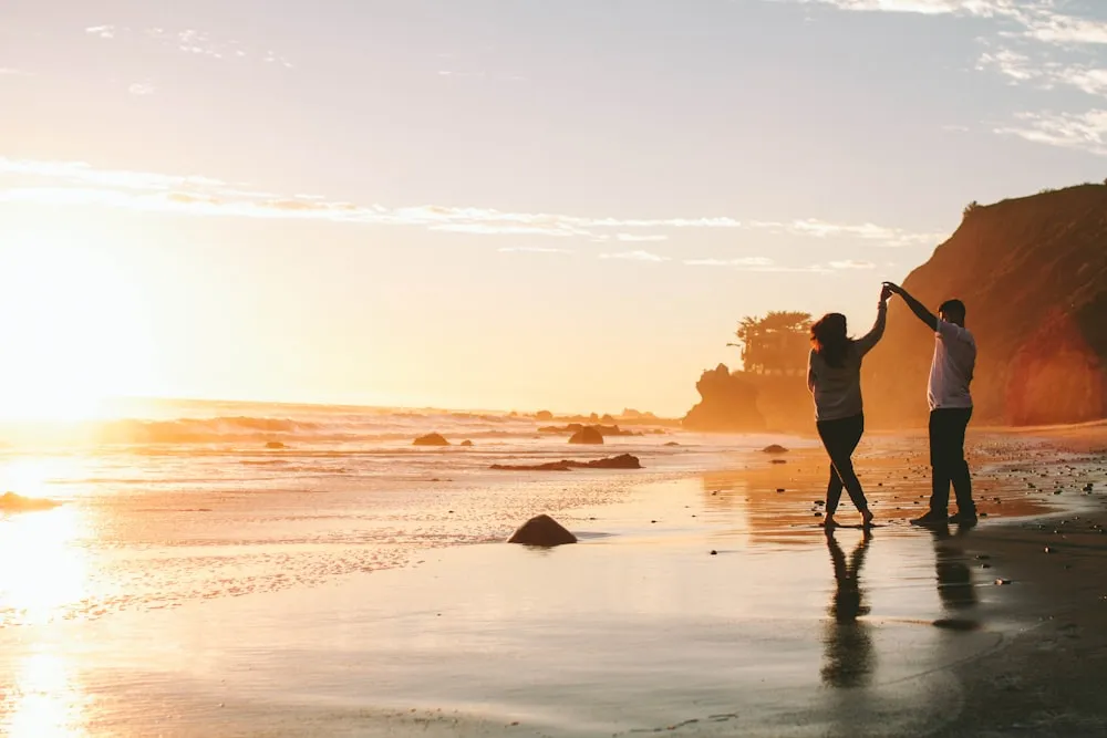 A couple standing close together on a beach.